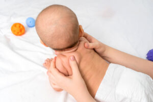 Hands of mother doing back massage for newborn baby. Selective focus